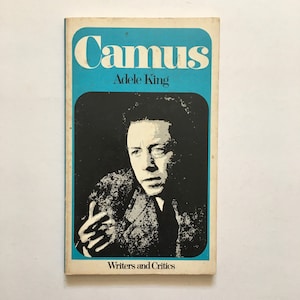 Może przedstawiać: Okładka książki w kolorze niebieskim i czarnym z tytułem "Camus" w dużych białych literach i autorem "Adele King" w mniejszych białych literach. Okładka zawiera r&oacute;wnież czarno-białe zdjęcie Alberta Camusa, francuskiego filozofa i pisarza, oraz słowa "Writers and Critics" na dole.