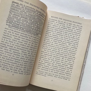 May include: A page from a book titled "Beyond the Pleasure Principle" by Sigmund Freud. The text discusses the development of the pleasure principle and how it is cut off by the reality principle. The text is in black and white and the page number is 7.