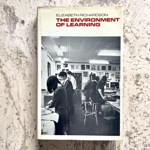 May include: A vintage book titled "The Environment of Learning" by Elizabeth Richardson. The cover is white with red text. The image on the cover is a black and white photo of a classroom with students.