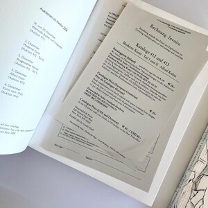 May include: A close-up of a document with the title "Rechnung Invoice" and the text "Moderne Kunst Teil I und II Alfred Kubin Kataloge 412 und 413" printed on it. The document lists prices for catalogs in different countries, including Germany, Europe, and the USA.