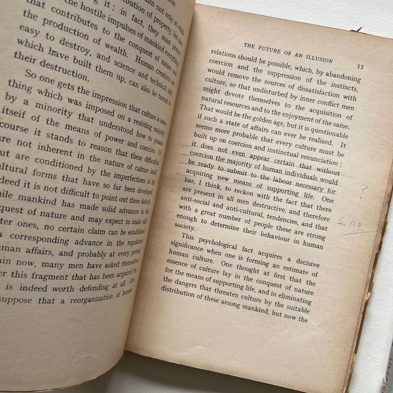 May include: A close-up of a book titled "The Future of an Illusion" by Sigmund Freud. The book is open to a page with text about the nature of culture and the role of coercion in society.