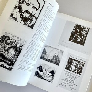 May include: A black and white book with a page open to a section on the artist Erich Heckel. The page features black and white illustrations of various art pieces, including a portrait of a man, a landscape, and a mountain scene. The page also includes text in German about the artist and his work.