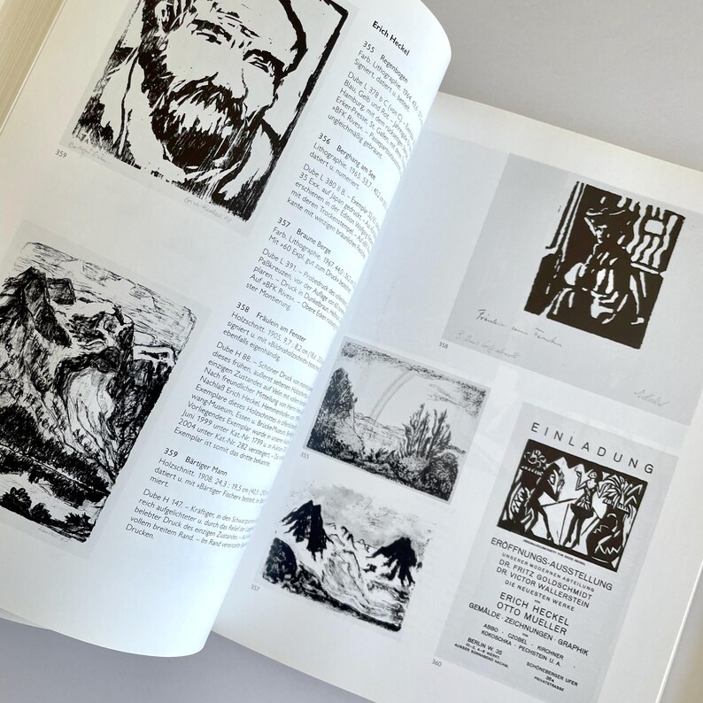 May include: A black and white book with a page open to a section on the artist Erich Heckel. The page features black and white illustrations of various art pieces, including a portrait of a man, a landscape, and a mountain scene. The page also includes text in German about the artist and his work.