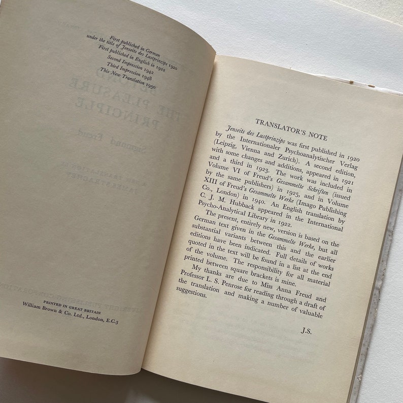 May include: A book titled "Beyond the Pleasure Principle" by Sigmund Freud. The book cover is white with black text. The book was first published in 1920 and is a translation of the German text.