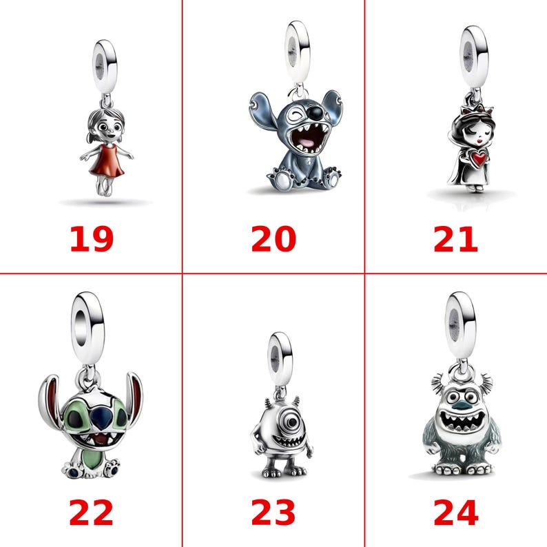 Op de afbeelding: Een collectie van zes zilverkleurige metalen bedels, genummerd van 19 tot 24. De bedels tonen verschillende animatiefiguren, waaronder een meisje in een rode jurk, een blauwe alien, een prinses met een hart, een groene alien en twee monsters.