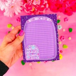 May include: A purple card with a sparkly background and the text "Read More Books" in a white, glittery font. The card has a lined section for writing and a small illustration of a bookshelf with colorful books.