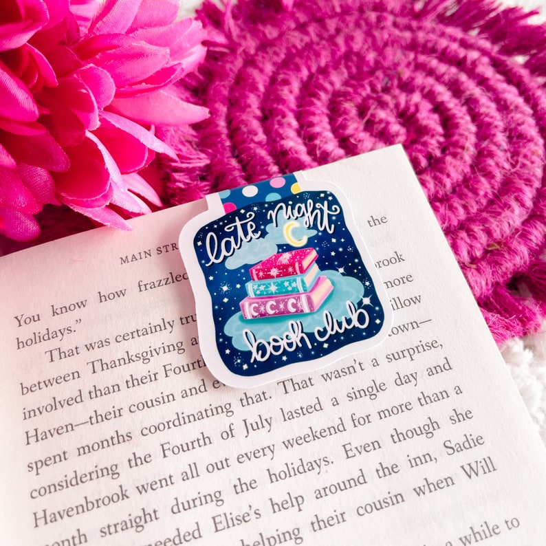 May include: A sticker with a blue background and a stack of books with stars and a crescent moon on top. The text "late night book club" is written in white on a cloud.