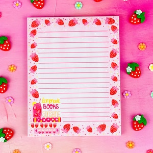 Puede incluir: Un bloc de notas rosa y blanco con un borde de fresas y la frase "lemonade, books, and sunshine". El bloc de notas tiene líneas horizontales para escribir y está decorado con fresas y flores.