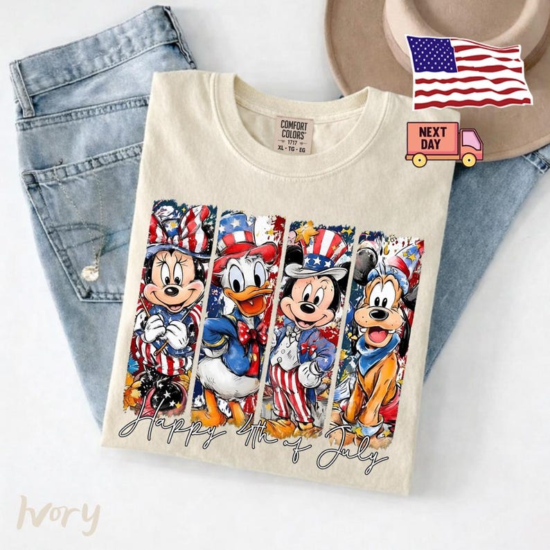 May include: An ivory t-shirt featuring a graphic print of four cartoon characters wearing patriotic red, white, and blue outfits. The design includes the text Happy 4th of July in a cursive script. The shirt is displayed alongside blue denim jeans.