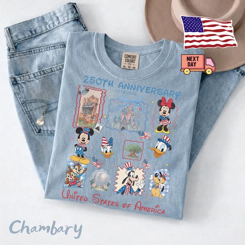 May include: A light blue t-shirt featuring a 250th Anniversary 1776-2024 graphic with illustrations of Mickey Mouse, Minnie Mouse, Donald Duck, Daisy Duck, Goofy, Pluto, Chip, Dale, and Disney landmarks, with the text United States of America.