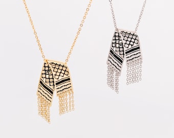 May include: Two delicate necklaces with a geometric pattern and fringe detail. One necklace is gold and the other is silver.