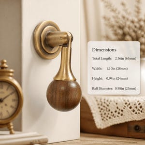Può includere: Un pomello per mobili in ottone e legno scuro con base rotonda, collo cilindrico e impugnatura sferica in legno. Le dimensioni sono: lunghezza totale 65 mm, larghezza 28 mm, altezza 24 mm e diametro della sfera 25 mm.