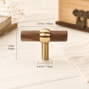 May include: A T-shaped cabinet knob featuring a dark brown wooden horizontal bar connected to a brushed brass metal center and base. The knob measures 1.97 inches in width, 1.30 inches in total height, and has a base diameter of 0.67 inches.