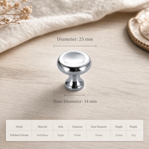 May include: A polished chrome cabinet knob with a round, smooth top and a tapered base. The knob has a diameter of 25 mm and a base diameter of 14 mm. A table below specifies a finish of polished chrome, solid brass material, 23 mm height, and 35 g weight.