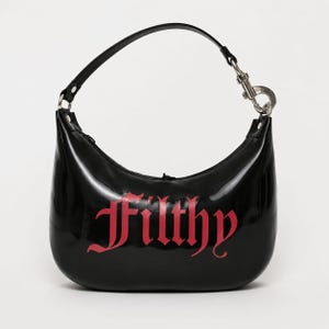 Puede incluir: Un bolso hobo negro brillante con forma de media luna y una sola correa para el hombro sujeta por un clip de metal plateado. La palabra Filthy está impresa en la parte delantera con una fuente gótica roja. El bolso tiene un acabado liso.
