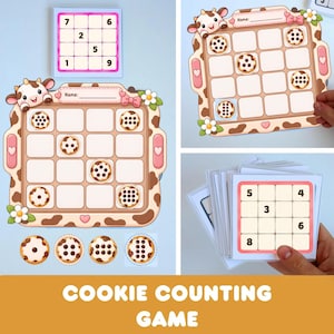Pode incluir: Um jogo de contagem de biscoitos com um tabuleiro de grade com tema de vaca, campo para nome, conjunto de cartões quadrados com números e fichas circulares de biscoitos com quantidades variadas de gotas de chocolate.