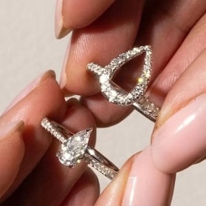 Peut inclure: Un ensemble de deux bagues en argent composé d'une bague solitaire en forme de poire et d'un protège-bague assorti en forme de poire. Les deux bagues sont en métal argenté poli et incrustées de petits diamants pavés clairs et étincelants.