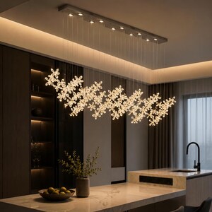 May include: A rectangular ceiling-mounted light fixture featuring numerous clear, flower-shaped crystal pendants suspended at varying heights by thin wires, creating a cascading, illuminated floral arrangement above a kitchen island.