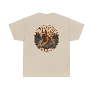 May include: A beige t-shirt featuring a circular graphic on the back. The design depicts a brown Belgian Malinois dog running through a forest with mountains in the background. The text BELGIAN MALINOIS is arched around the circle with GET STUFF DONE.