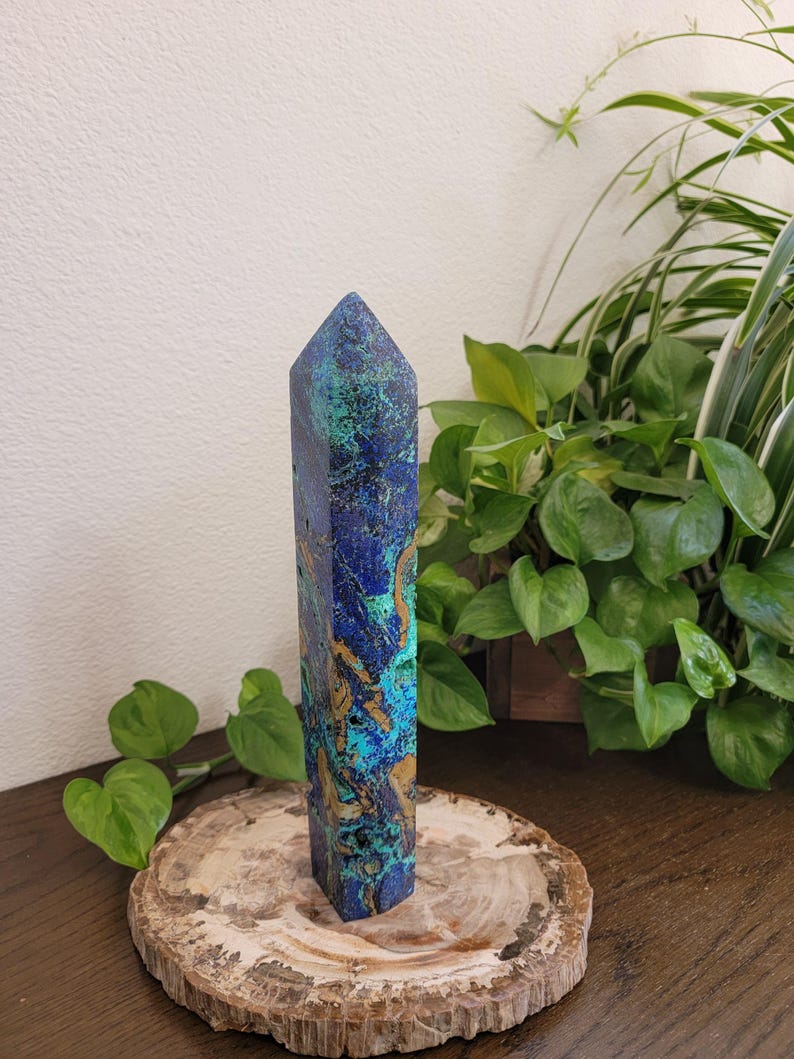May include: A tall, faceted crystal tower featuring a vibrant, marbled pattern of deep royal blue, bright turquoise, and earthy tan mineral inclusions. The stone has a polished, smooth surface with a pointed, pyramidal top and a hexagonal base.