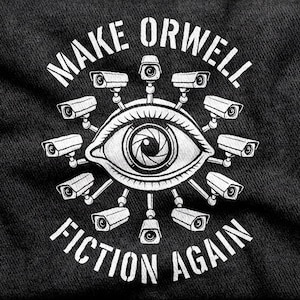 May include: A black t-shirt featuring a white graphic print of a large human eye with a camera lens iris. The eye is surrounded by ten surveillance cameras arranged in a circle. The text "MAKE ORWELL FICTION AGAIN" is printed in white.