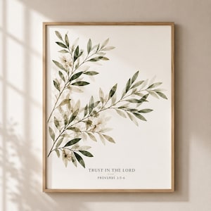 Puede incluir: Una lámina de arte mural enmarcada con ramas de olivo verdes estilo acuarela sobre un fondo crema. El texto "TRUST IN THE LORD" y "PROVERBS 3:5-6" está impreso en negro en la parte inferior central de la composición rectangular vertical.