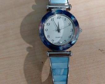 Vintage, silver tone watch with blue accents in wrist band and on the round case