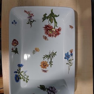 May include: A rectangular white ceramic serving dish featuring a scattered botanical pattern of various colorful flowers, including red, orange, yellow, blue, and purple blossoms, interspersed with small detailed illustrations of butterflies.
