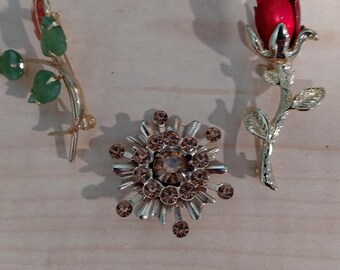 Set of three vintage brooches-pins.  One jade rose, one red rose, one brown rhinestone starburst