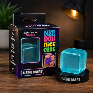Op de afbeelding: Een doorschijnend lichtblauw squishy kubusspeeltje met het label Nee Doh Nice Cube van Usmi Mart. De zwarte verpakking bevat de tekst Super Solid Squish, Durable, Squishy en Stress Relief met iconen. Een bijpassende blauwe kubus staat op een zwarte displayvoet.