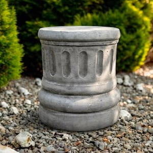 May include: A cylindrical gray concrete garden pedestal featuring a smooth top surface, a central section with vertical recessed fluting, and a rounded base. The structure has a weathered stone texture and a solid, sturdy appearance.