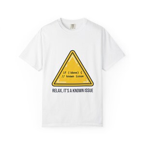 Puede incluir: Camiseta blanca con un letrero de advertencia triangular amarillo. El letrero tiene el texto "if (!done) { // known issue" y "RELAX, IT'S A KNOWN ISSUE" en negro. Una prenda de vestir informal.