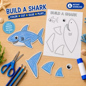 May include: A Build a Shark activity sheet with black and white outlines of shark parts, a blue colored-in shark cutout, blue colored shark fins, a blue glue stick, blue scissors, and blue pencils. The text reads Build a Shark and Color Cut Glue Play.