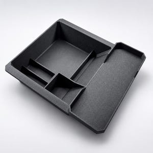 May include: A dark gray, multi-compartment organizer tray. The tray has a rectangular shape with several sections of varying sizes, including a larger square area and smaller rectangular slots. The surface has a textured appearance.