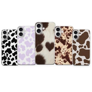 Peut inclure: Cinq coques de smartphone alignées, chacune présentant un motif de taches de vache distinct. Les designs incluent noir et blanc, violet clair et blanc, texture fourrure marron et blanc avec un cœur, marron et blanc moucheté, et taches marron et blanc. Chaque coque a une découpe pour l'appareil photo.