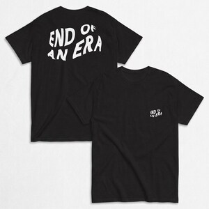 Puede incluir: Una camiseta negra de manga corta con el texto blanco END OF AN ERA en una fuente ondulada. La parte posterior de la camiseta muestra el texto en un tamaño grande, mientras que el área del pecho frontal presenta el mismo texto en versión pequeña.