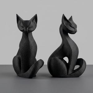 Può includere: Due statuette di gatto nere con una superficie ruvida. Ogni gatto è raffigurato in posizione seduta con la schiena arcuata, orecchie a punta e una lunga coda avvolta attorno alla base. Le figure hanno una finitura opaca e sono posizionate vicine.