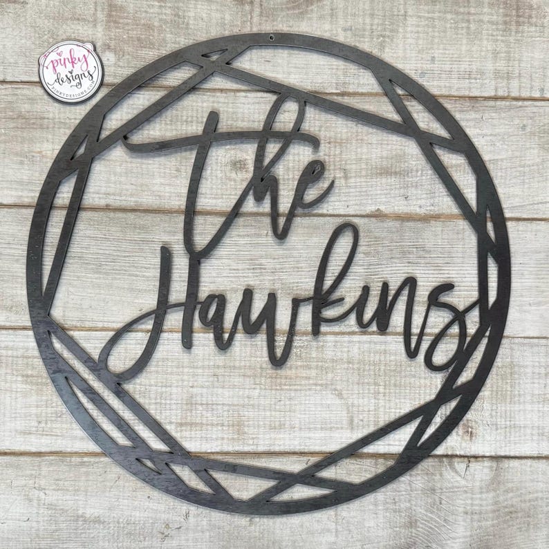 May include: Black metal wreath with a geometric design. The text "The Hawkins" is written in a cursive font.