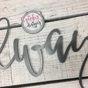 A metal always sign is laid on a light wood background. The metal is left raw metal to show the patina of the natural metal. There is a pinky designs logo located above the metal piece