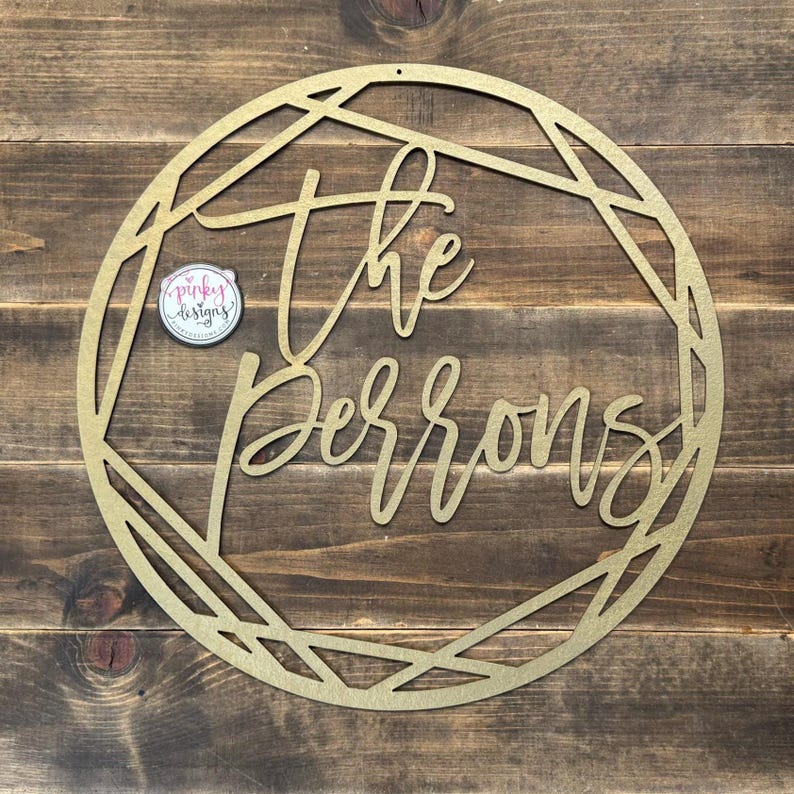 May include: Gold metal circle with a geometric design and the text "The Perrons" in a cursive font.