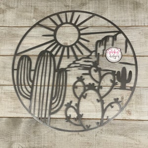 May include: A metal wall art piece depicting a desert scene with a sun, mountains, and cacti. The art is circular and has a black outline.