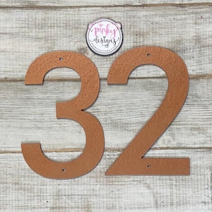 May include: Copper house numbers 32, with a textured finish, on a wood background.