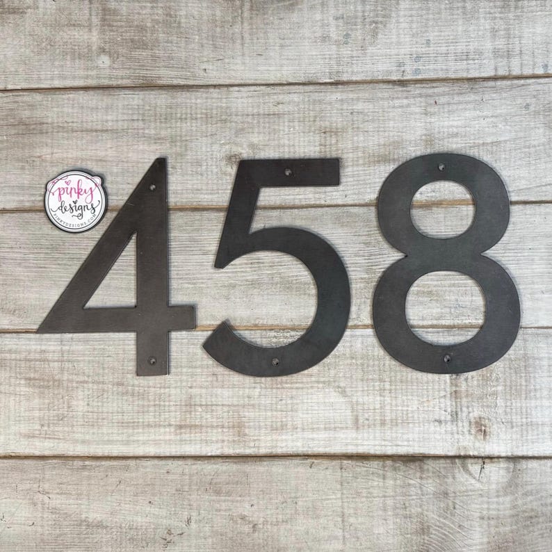 May include: Black metal house numbers 4, 5, and 8. The numbers are cut out and have a rustic look.