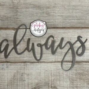 A metal always sign is laid on a light wood background. The metal is left raw metal to show the patina of the natural metal. There is a pinky designs logo located above the metal piece