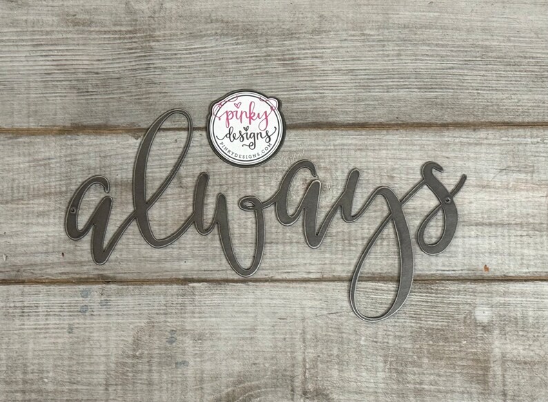 A metal always sign is laid on a light wood background. The metal is left raw metal to show the patina of the natural metal. There is a pinky designs logo located above the metal piece