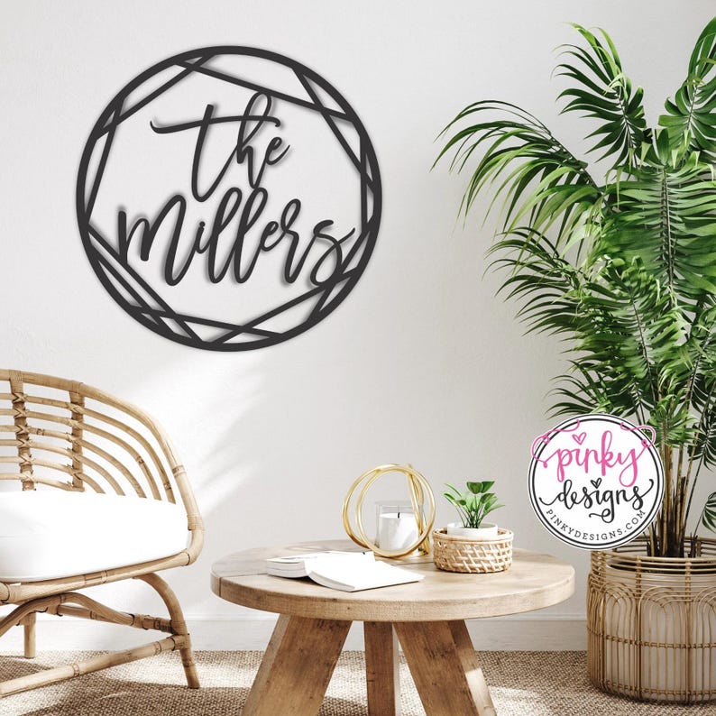 Large metal wall art piece mounted on a light interior of a home. Below is a boho looking living room. There is a wick chair on the left side of the room next to a light wooden table, a wick planter sits to the right with a large plant inside of it.