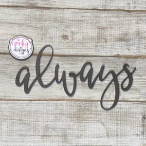 May include: A metal sign with the word "always" written in a cursive font. The sign is painted a dark gray color and is mounted on a white wooden background.