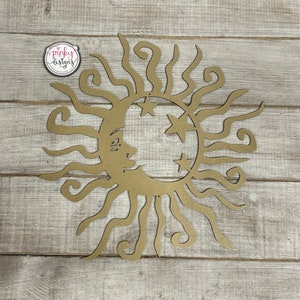 May include: Gold metal sun and moon wall decor with a crescent moon and three stars. The sun has a face and curly rays.