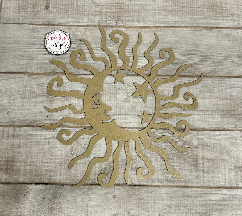 May include: Gold metal sun and moon wall decor with a crescent moon and three stars. The sun has a face and curly rays.