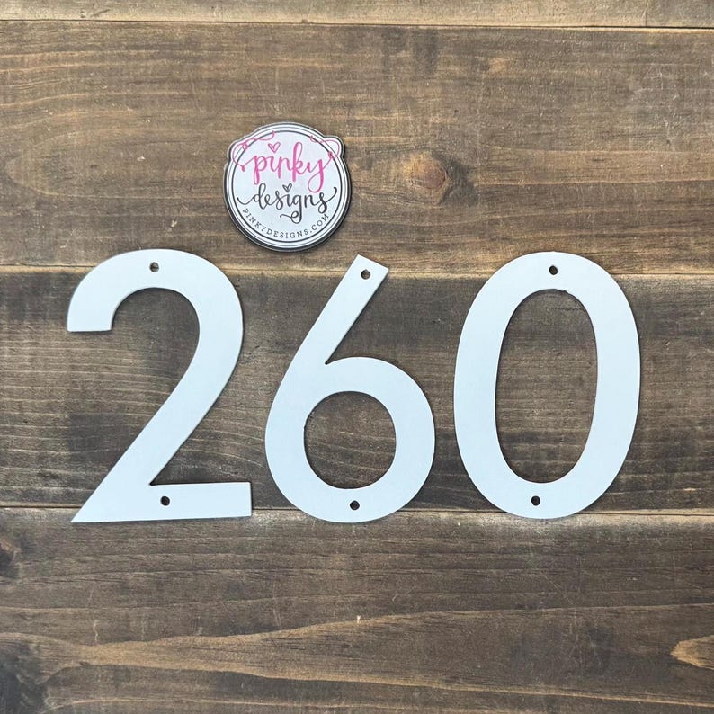 May include: White metal house numbers 260. The numbers are cut out and have holes for mounting.